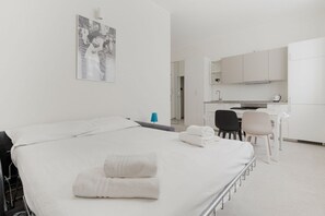 Ein Hotelzimmer mit Bett, Schreibtisch, Stuhl und Küchenzeile.