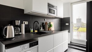 Una cocina moderna con lavadora integrada, cafetera y microondas.