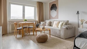 Una sala moderna con un sofá, una mesa redonda de centro y un comedor con sillas y una mesa.