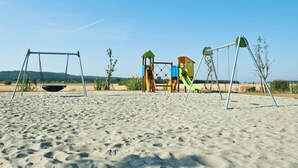 Una playa arenosa con un columpio y un parque infantil.