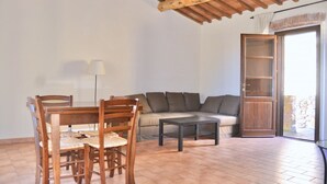 Una sala de estar con una mesa de comedor de madera, sillas, un sofá y una mesa baja.