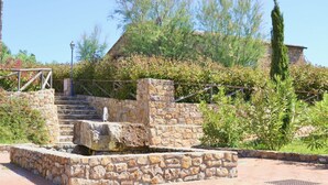 Una escalera de piedra que sube hacia una casa con un muro de piedra y una barandilla de metal.
