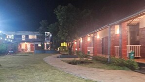 A building with multiple rooms, a paved walkway, and a grassy area. - Aranyagiri Farm Stay (Rameghar)