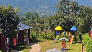 A playground with swings, slides, and a climbing structure. - Aranyagiri Farm Stay (Rameghar)