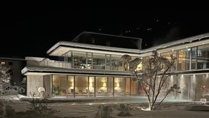 A modern building with large glass windows and a snow-covered ground.