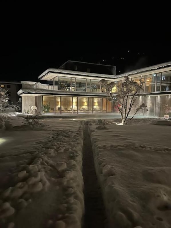 A modern building with large glass windows and a snow-covered ground.