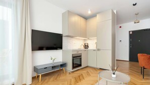 Eine moderne Küche mit Einbauofen, Kaffeemaschine und Wand-Fernseher.