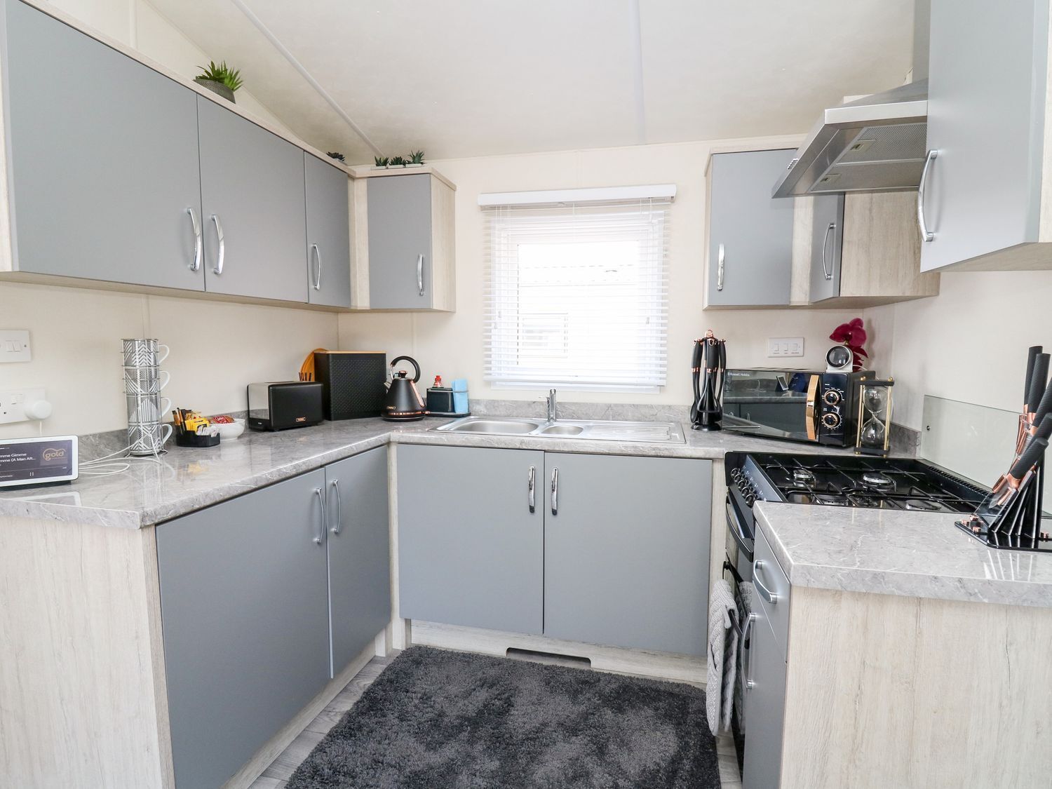 A modern kitchen with grey cabinets, a built-in oven, and a gas stove.