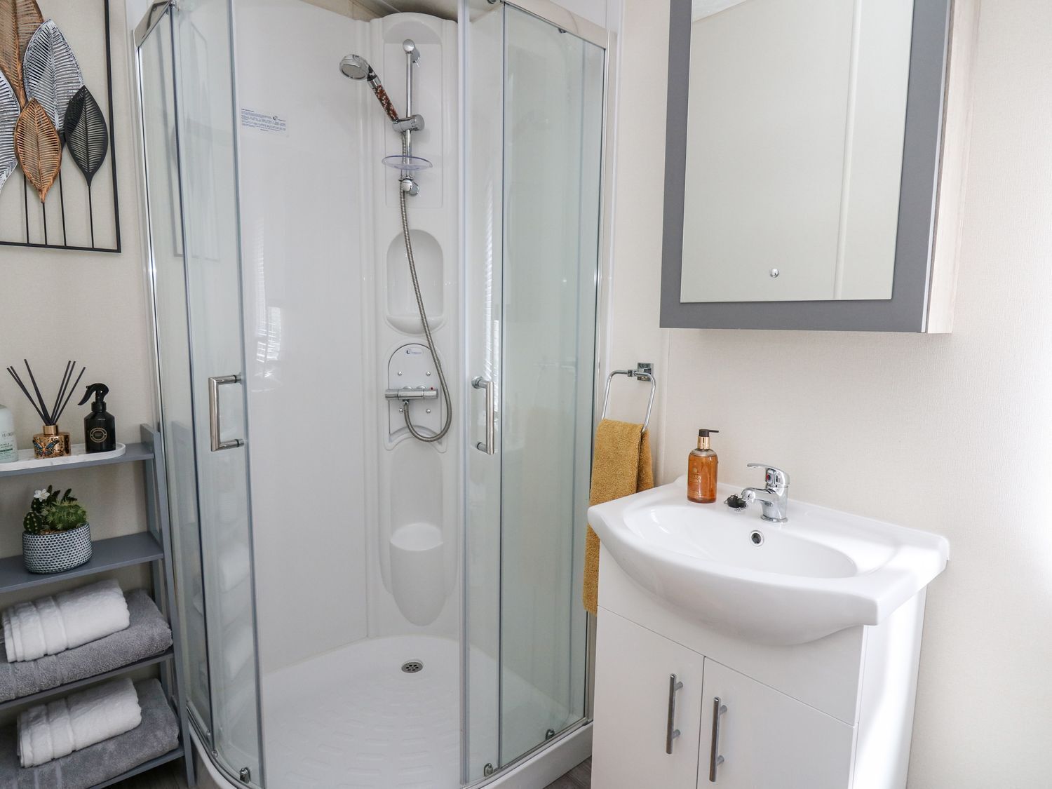Een moderne badkamer met een douchecabine van glas, een witte wastafel en een handdoekhouder.