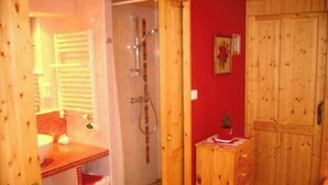 Un baño con ducha, lavamanos y un armario de madera.