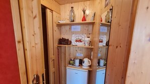 Cocina pequeña con armarios de madera, un refrigerador blanco y diversos utensilios y adornos de cocina.