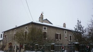 Un bâtiment en pierre doté de nombreuses fenêtres et dont le toit est recouvert de neige.