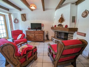 A cozy living room with a fireplace, wooden furniture, and a television.