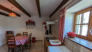 Une cuisine équipée d’une table, de chaises, d’un four à micro-ondes, d’un évier et d’une fenêtre avec des rideaux.