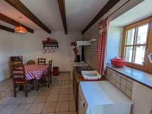 Une cuisine Ă©quipĂ©e dâune table, de chaises, dâun four Ă micro-ondes, dâun Ă©vier et dâune fenĂȘtre.