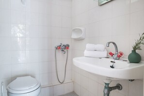 Een badkamer met toilet, wastafel en douche.