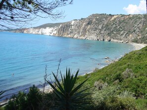 Paisatge costaner amb mar blau turquí, penya-segats rocosos i vegetació abundant.
