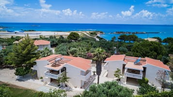 Um hotel à beira-mar com edifícios de dois andares, uma piscina e vista para o mar.