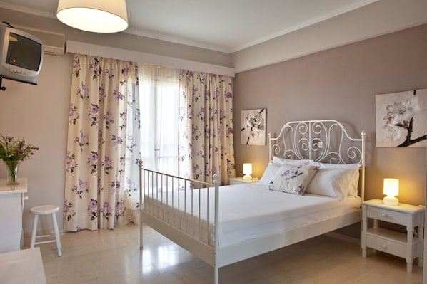 A bedroom with a bed, nightstands, a TV, and curtains. - Mirtia Studios (Kefalonia)