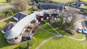 A large, modern house with a curved roof and a patio area. - Nestled in an elevated position with sweeping views across the Luxulyan Valley. (Penpillick)