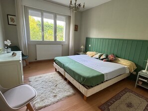 Ein Schlafzimmer mit Bett, Schreibtisch, Stuhl, einem Fenster mit Jalousien und einer Heizung.