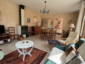 Ein Wohnzimmer mit Kamin, Essbereich und einer Couch mit Kissen.