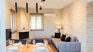 En moderne stue med spiseplads, en sofa og en pejs.