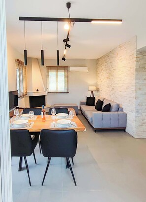 Ein modernes Wohnzimmer mit Essbereich, einer Couch und einem Kamin.
