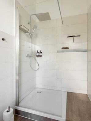 Eine moderne Dusche mit Glastrennwand, Handbrause und fest installierter Bedienung.