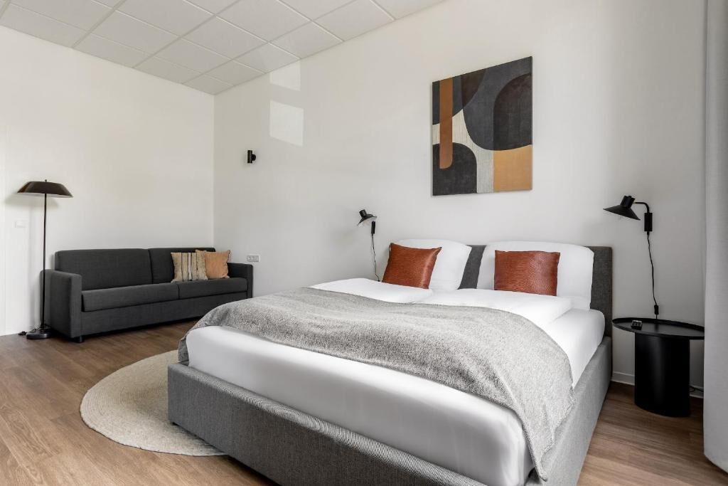Une chambre à coucher moderne avec un lit, un canapé et un tableau au mur.