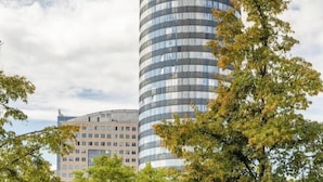 Ein zylindrisches Hotel mit einer glänzenden Glasfassade und einem sichtbaren Logo auf dem Dach.