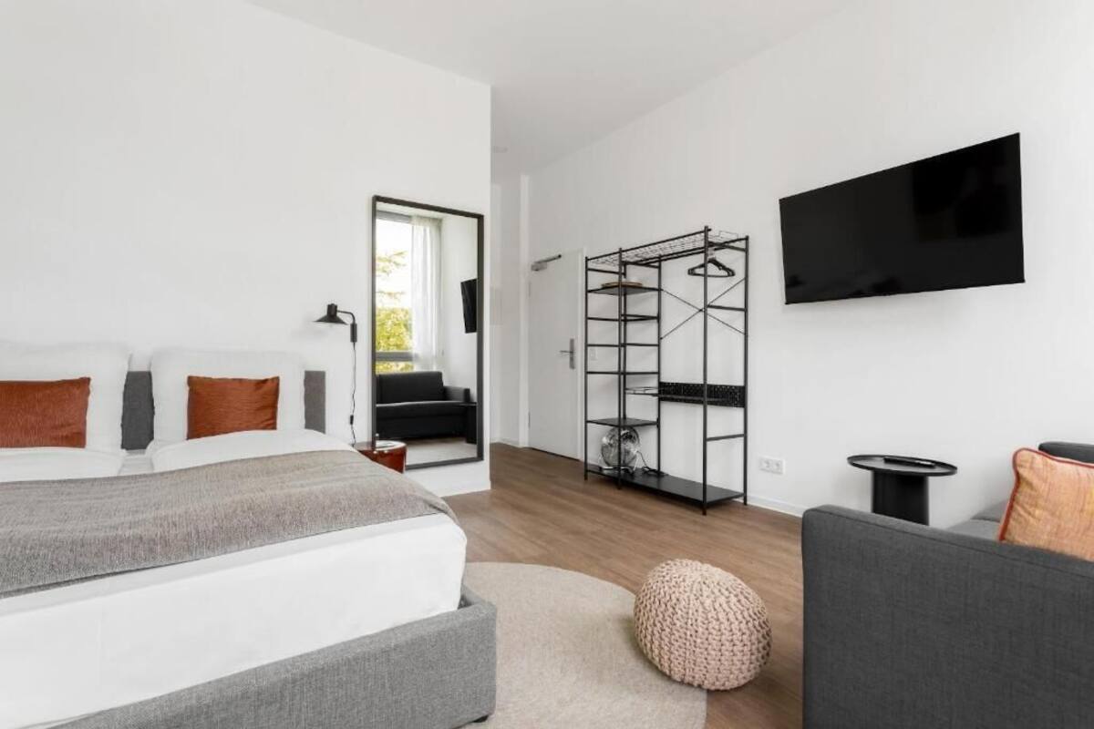 A modern bedroom with a bed, a TV, a wardrobe, and a small table.