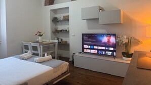 A modern hotel room with a bed, a desk, a television, and a small balcony with a brick arch. - ACasaDiImma Vicino Metro Wi-Fi Luminoso (Milan)