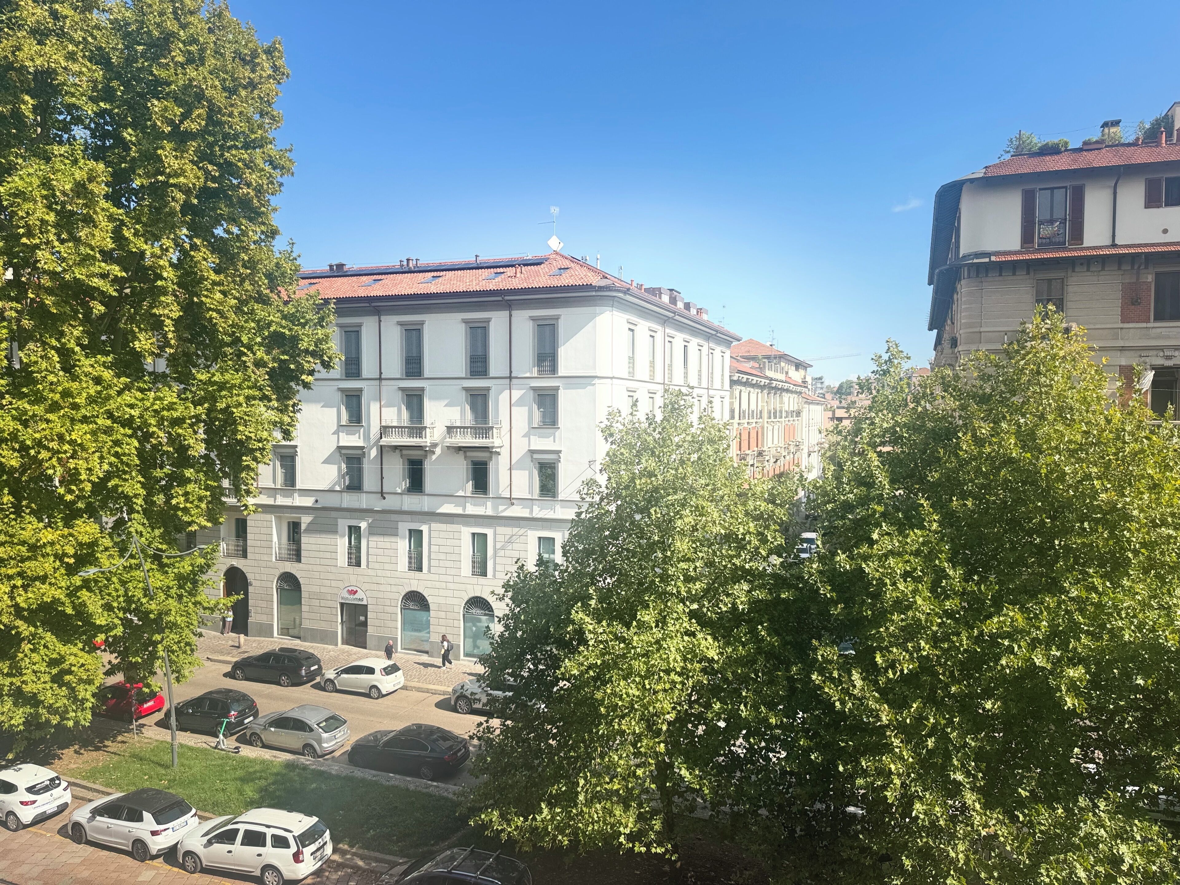 A multi-story building with a red-tiled roof, white walls, and multiple balconies.