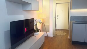 A modern living room with a flat-screen TV, a small table with a potted plant, a lamp, and a door leading to another room. - ACasaDiImma Vicino Metro Wi-Fi Luminoso (Milan)