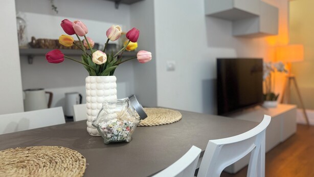 A modern dining area with a white vase of tulips, a glass jar, and woven placemats on a dark table. - ACasaDiImma Vicino Metro Wi-Fi Luminoso (Milan)