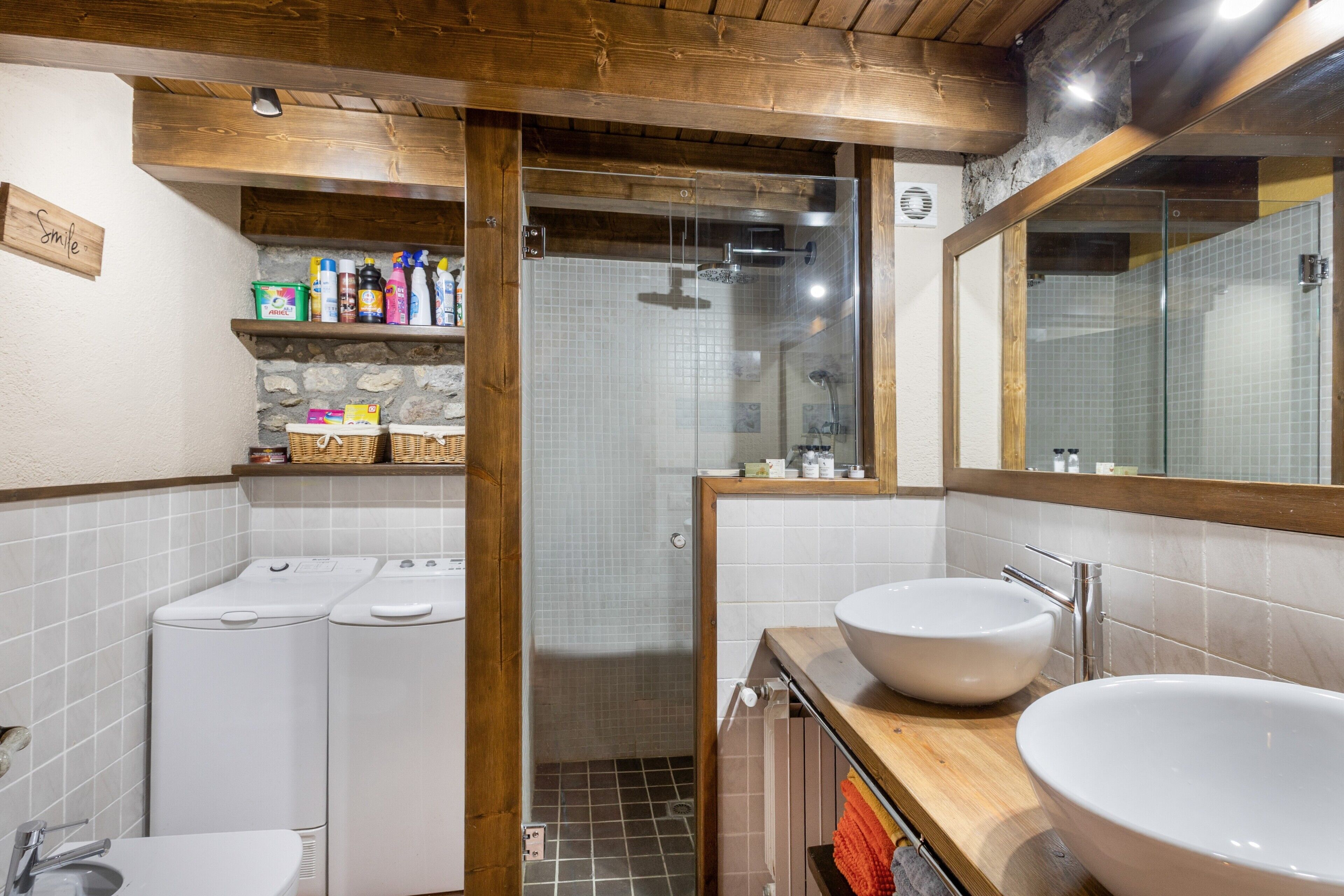 Un baño con dos lavamanos, ducha y zona de lavandería.