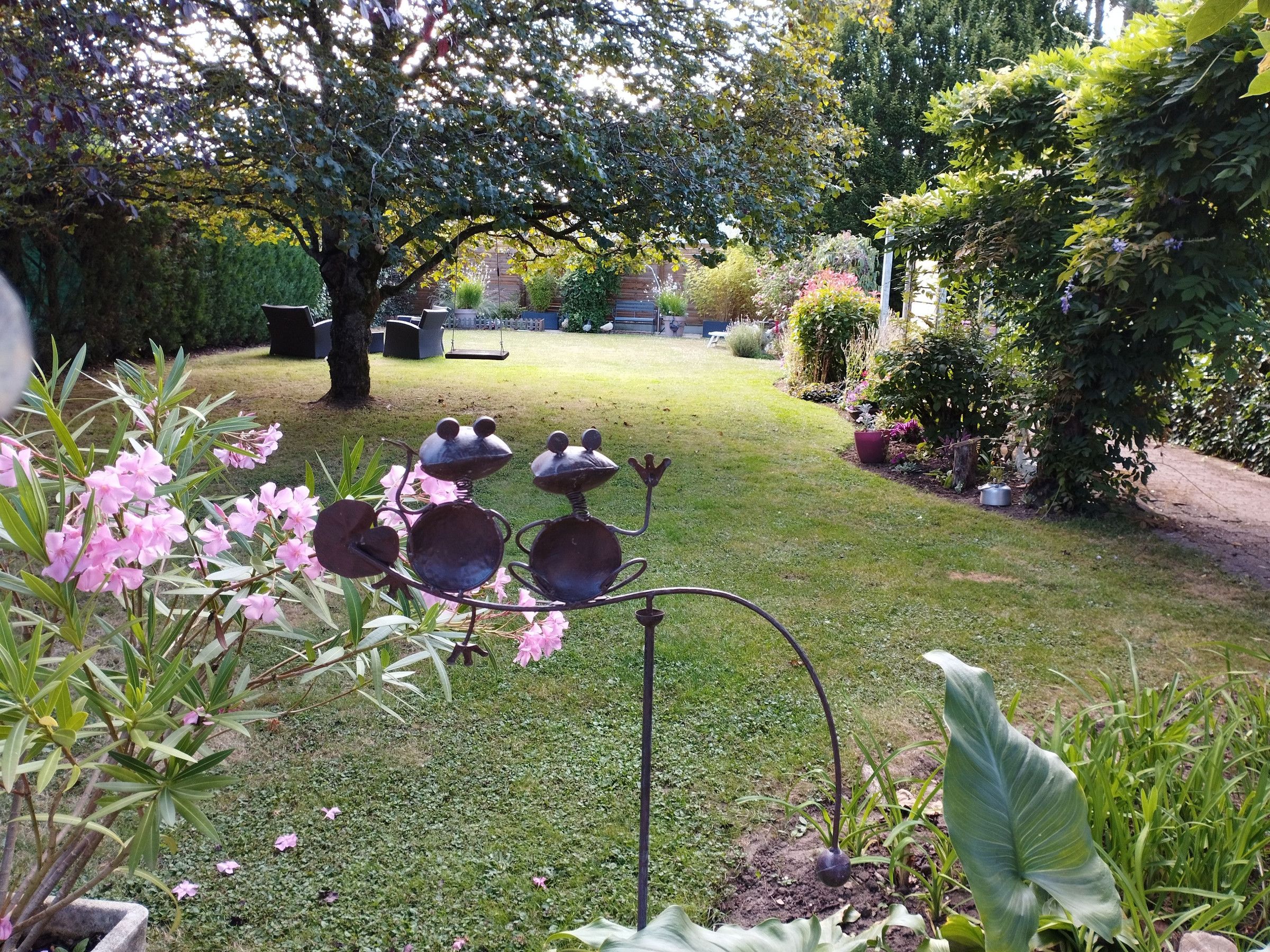 Un jardin agrémenté d’une sculpture en métal, d’une pelouse et de diverses plantes.