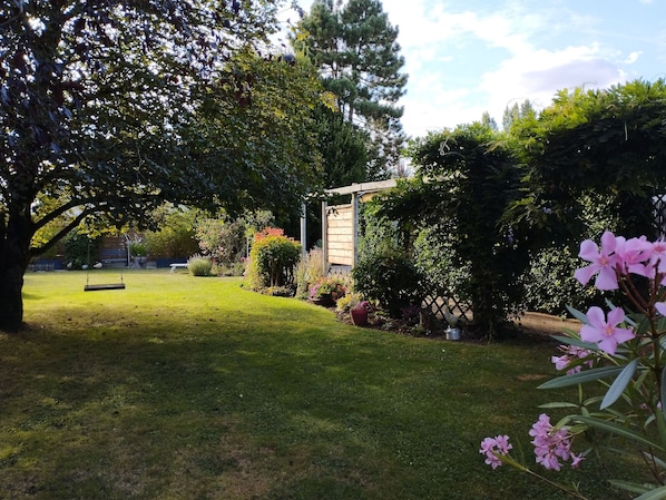 A well-maintained garden with a swing, a wooden fence, and various plants.