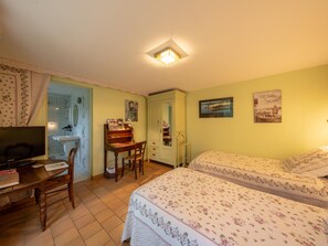 A bedroom with a bed, a desk with a chair, a TV, and a bathroom visible through an open door. - Room Châteauneuf: Rustic Charm with Private Terrace and Wifi in Saint-Benoît-sur-Loire (Saint-Benoît-sur-Loire)
