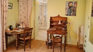 Une pièce chaleureuse avec une table en bois, deux chaises, un radiateur, un tableau et une porte donnant sur une autre pièce.