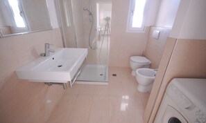 A modern bathroom with a large sink, a shower, and a toilet. - Relax in our sea View Flat (Lignano Sabbiadoro)