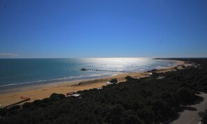 A coastal landscape with a beach, a pier extending into the sea, and a road leading to a settlement. - Relax in our sea View Flat (Lignano Sabbiadoro)
