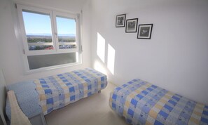 A bedroom with two single beds, a window with a view, and three framed pictures on the wall. - Relax in our sea View Flat (Lignano Sabbiadoro)