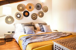Een keurig opgemaakt slaapkamer met een bed, kussens, een dekbed en decoratie aan de muur.