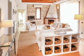A modern living room with a fireplace, white furniture, and wicker baskets. - Villa Erika SicilyMyHome (Ispica)