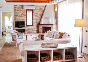 A cozy living room with a fireplace, a sofa, a television, and wicker baskets. - Villa Erika SicilyMyHome (Ispica)