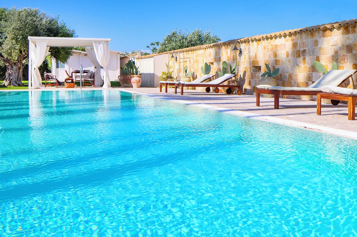A clear blue pool with lounge chairs and a pergola.