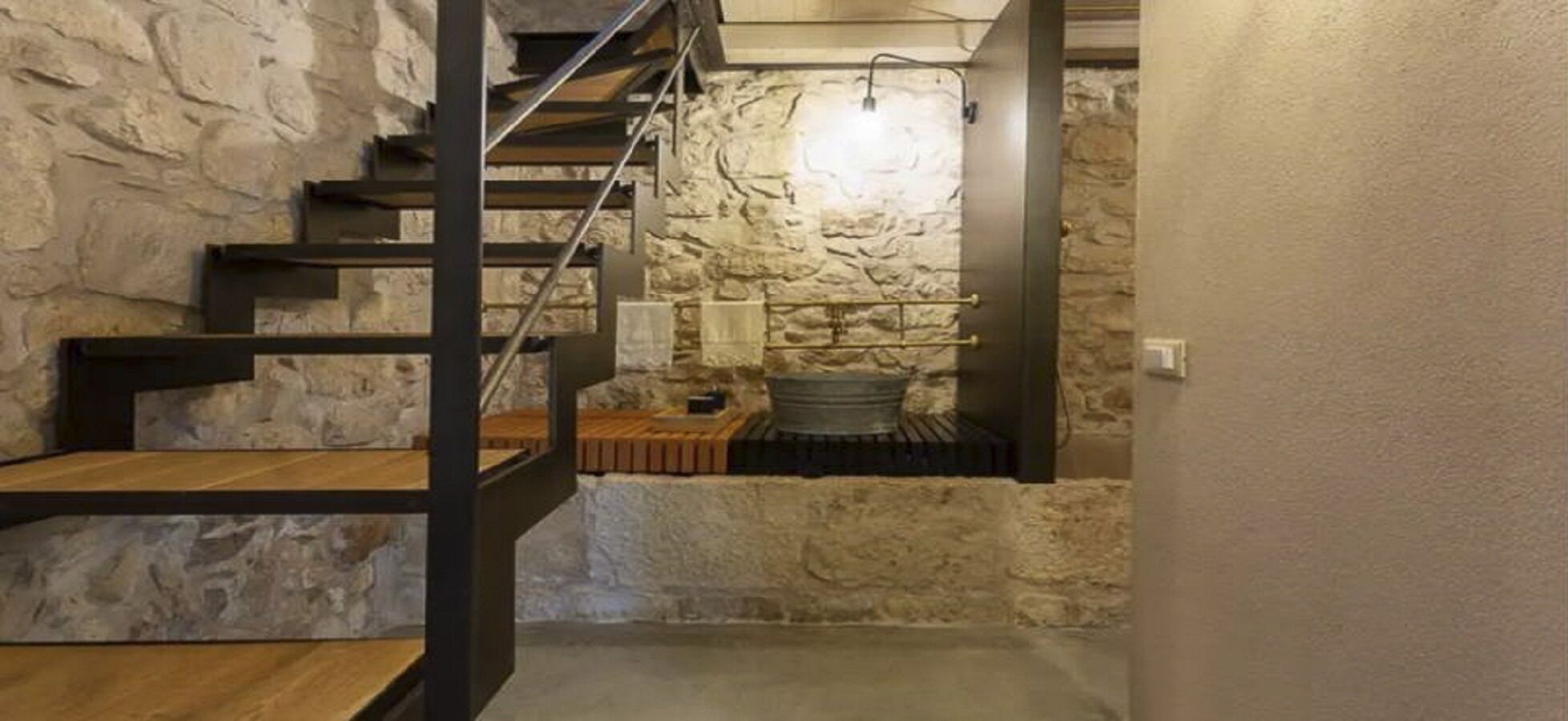 Una escalera conduce a una habitación de paredes de piedra con chimenea.