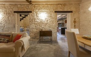 Ein Zimmer mit Stehwänden, einem Sofa, einem kleinen Tisch und einem Essbereich mit Stuhl und Tisch.